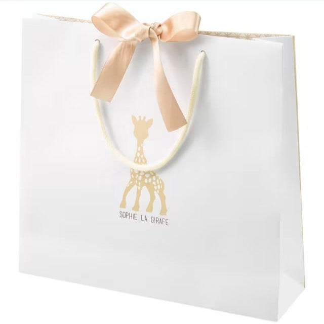 White gift bag with gold giraffe design and pink bow on a light gray background