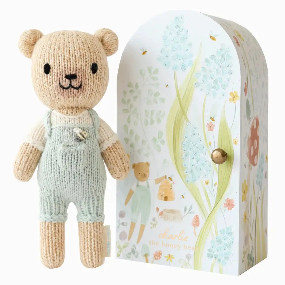 tiny charlie hand knitted bear in pale blue dungaree's with a honey bee