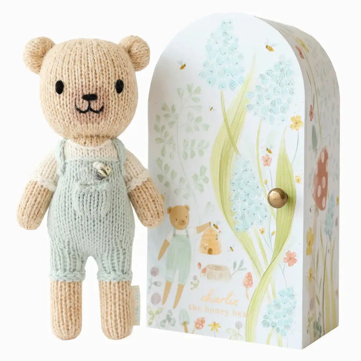 tiny charlie hand knitted bear in pale blue dungaree's with a honey bee