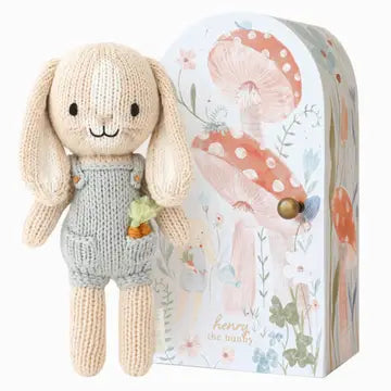 Knitted toy rabbit with a carrot in his pocket and light blue dungarees