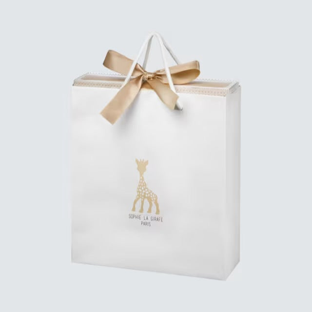 Gift bag with a gold bow and giraffe logo on a light gray background