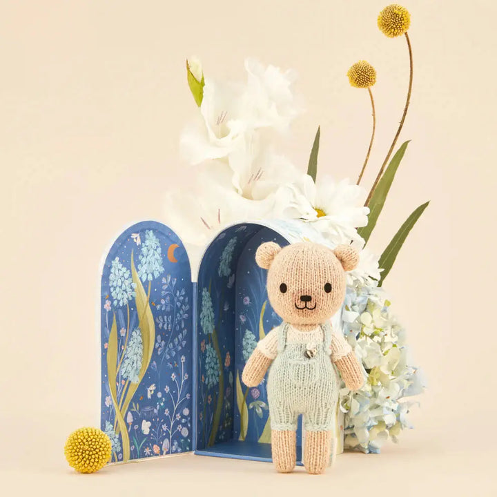tiny charlie hand knitted bear in pale blue dungaree's with a honey bee