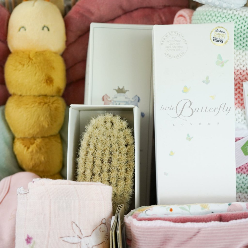 Pink butterfly baby girl hamper, baby clothing set, baby cotton knit blanket in pink, pink muslin with bunnies, large butterfly soft toy, soft fabric baby book in pink with butterflies and flowers, white cute baby shoes in white with bunny ears, baby hairbrush