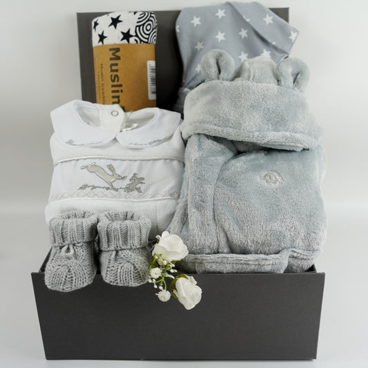 Grey hamper box with grey baby dressing gown with cute ears,  grey with white stars baby knot hat, white and black sensory muslin swaddle, grey knit baby booties, white and grey smoked Guess how much I love you baby sleepsuit