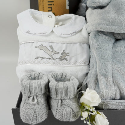 Grey hamper box with grey baby dressing gown with cute ears, grey with white stars baby knot hat, white and black sensory muslin swaddle, grey knit baby booties, white and grey smoked Guess how much I love you baby sleepsuit