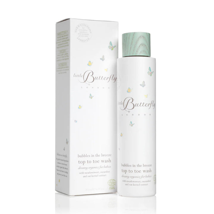A bottle of 'bubbles in the breeze' top to toe wash by 'little Butterfly London' stands next to its matching white packaging box. The bottle has a white body with a light green marbled cap, and both items are decorated with small pastel butterfly illustrations.