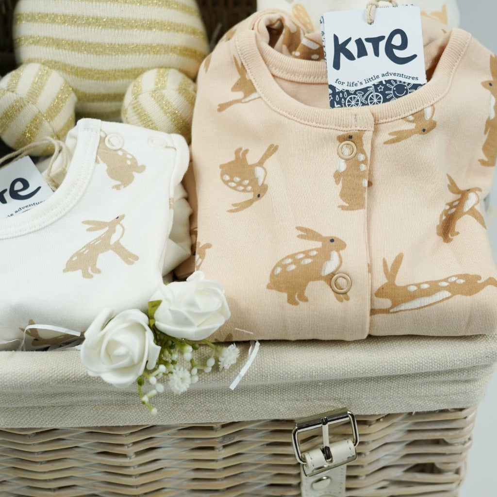 white wicker basket, grey star cotton baby blanket, gold and cream organic miffy, cream baby bodysuit with brown rabbits, caramel coloured sleepsuit with brown rabbit