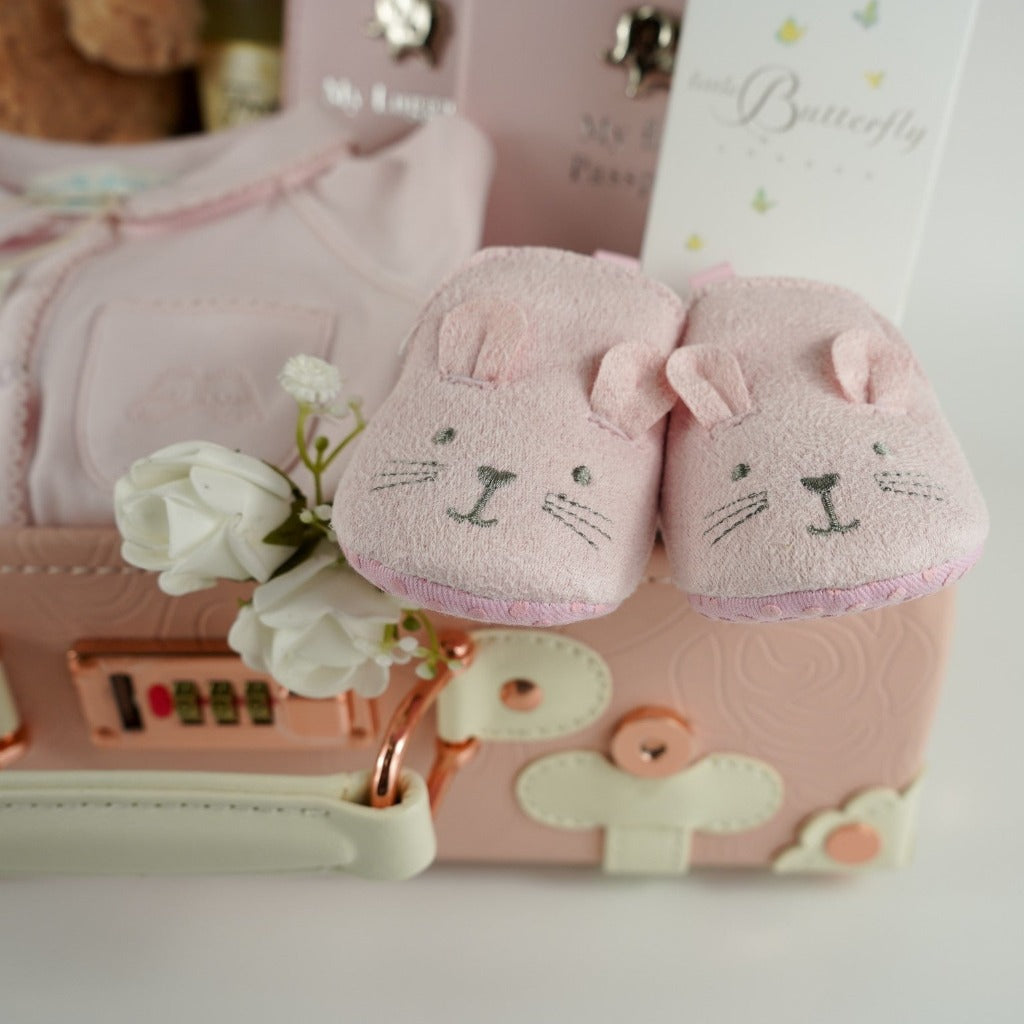 Pink baby suitcase with Steiff teddy, cashmere shawl, baby passport and luggage label, Marie Chantal pink baby sleepsuit, pink baby slippers with bunny ears , Butterfly London baby massage oil