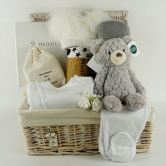 Pregnancy hamper basket with grey teddy, grey baby blanket with stars , black and white sensory baby swaddle, white baby hat with 2 Pom poms . White pregnancy journal. Pregnancy milestone discs, white baby clothing set includes jacket, bodysuit and leggings 