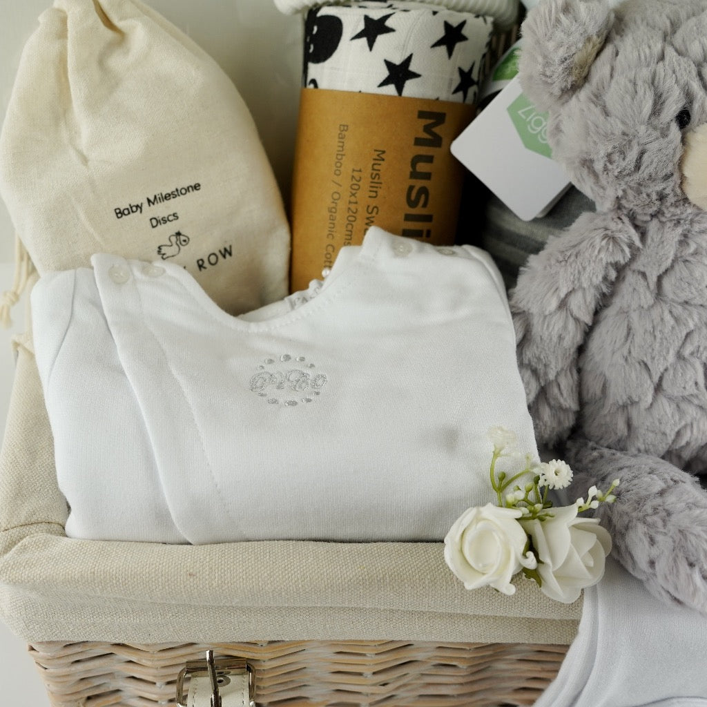 Pregnancy hamper basket with grey teddy, grey baby blanket with stars , black and white sensory baby swaddle, white baby hat with 2 Pom poms . White pregnancy journal. Pregnancy milestone discs, white baby clothing set includes jacket, bodysuit and leggings