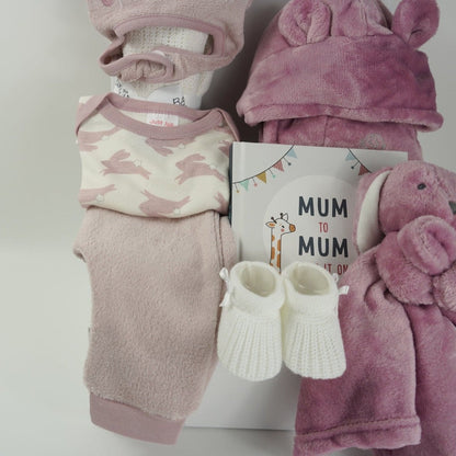 baby girl hamper box with three piece baby clothing set including pink fleece leggings, baby white body suit with pink rabbits, cute hat with bunny ears in pink, dusky pink baby dressing gown with cute ears, dusky pink fleece rabbit baby comforter, white knit baby bootees, hard back book with advice for new mums from other mums