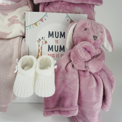 baby girl hamper box with three piece baby clothing set including pink fleece leggings, baby white body suit with pink rabbits, cute hat with bunny ears in pink, dusky pink baby dressing gown with cute ears, dusky pink fleece rabbit baby comforter, white knit baby bootees, hard back book with advice for new mums from other mums