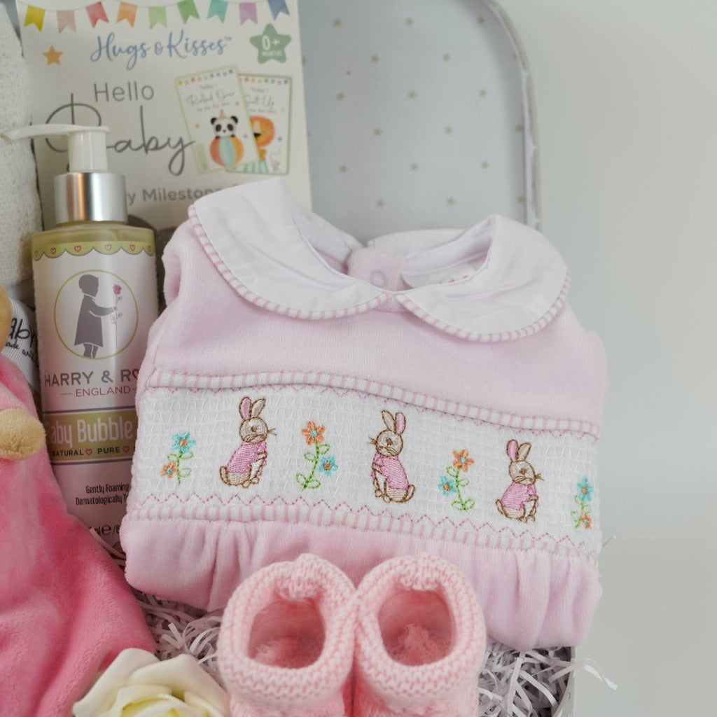 Baby girl hamper with flopsy bunny comforter in pink and white, baby cellular blanket, baby milestone cards , cute pink velour baby sleepsuit with smocked front with flopsy bunny, pink knit booties , baby organic wash