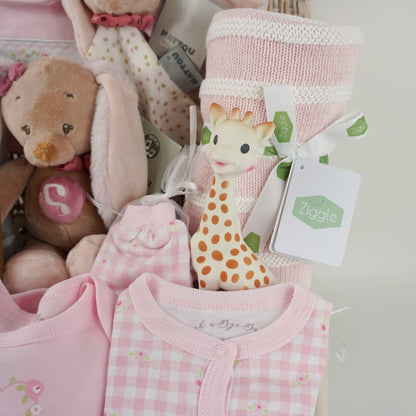 baby hamper basket with baby themed biscuits for mum, baby white muslin with bunnies, pink layette, musical baby bunny and matching comforter, baby pink shoes with cute ears , pink and white knit blanket