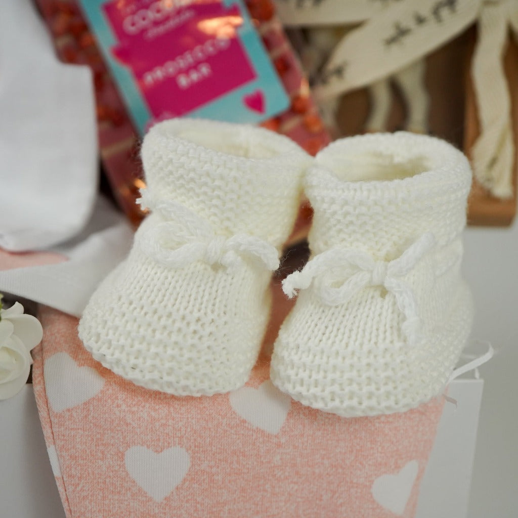 baby girl hamper box, baby top with pink and white filled collar and bow, applique hearts and circles in pink, pink leggings with white hearts, white booties, prosecco pink chocolate bar, pink baby blanket with stars, pink fluffy elephant soft toys, elephant teether