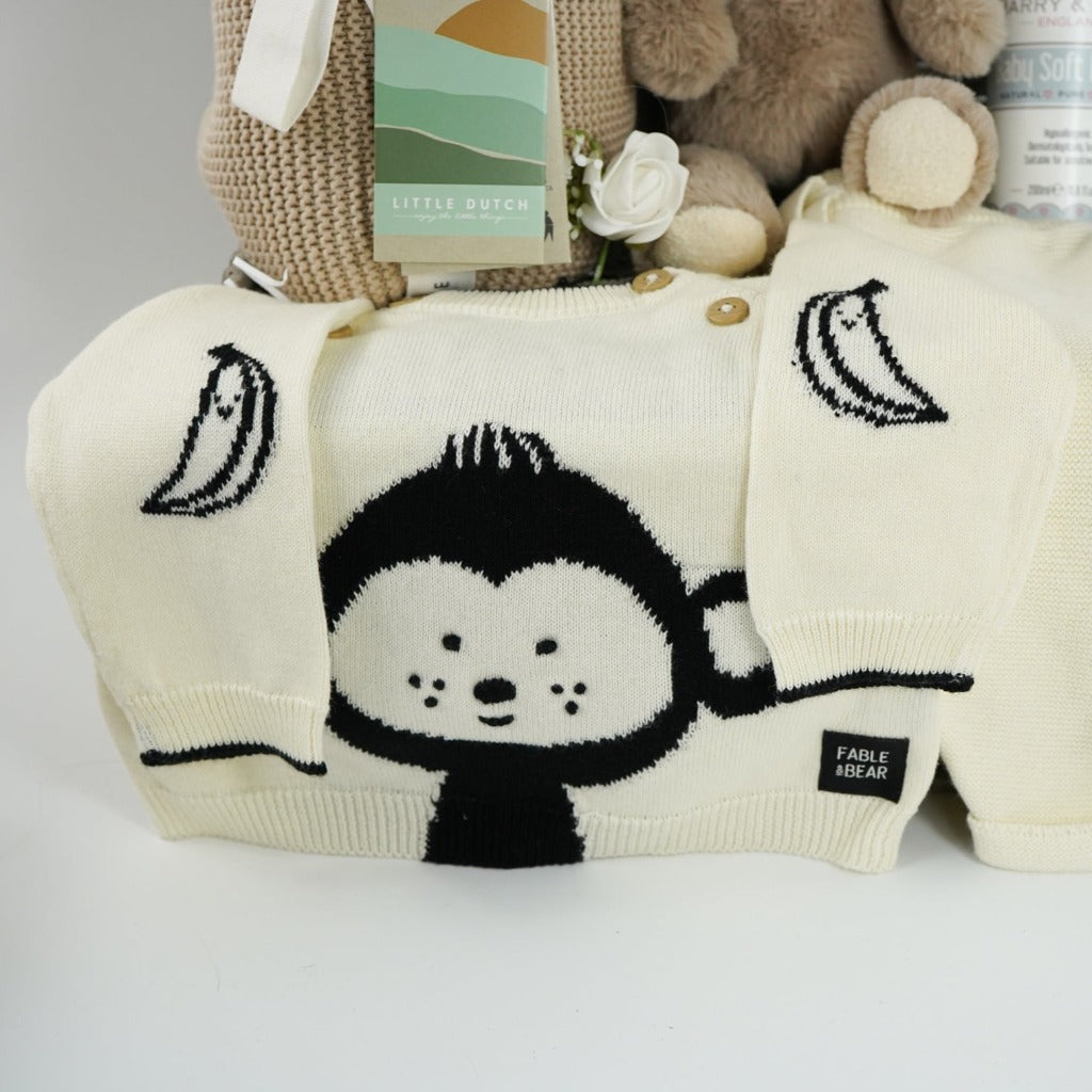 baby hamper with organi clothing set in cream with a black monkey face, soft organic blanket in beige, soft eco friendly monkey plush and matching monkey comforter, soft baby lotion organic