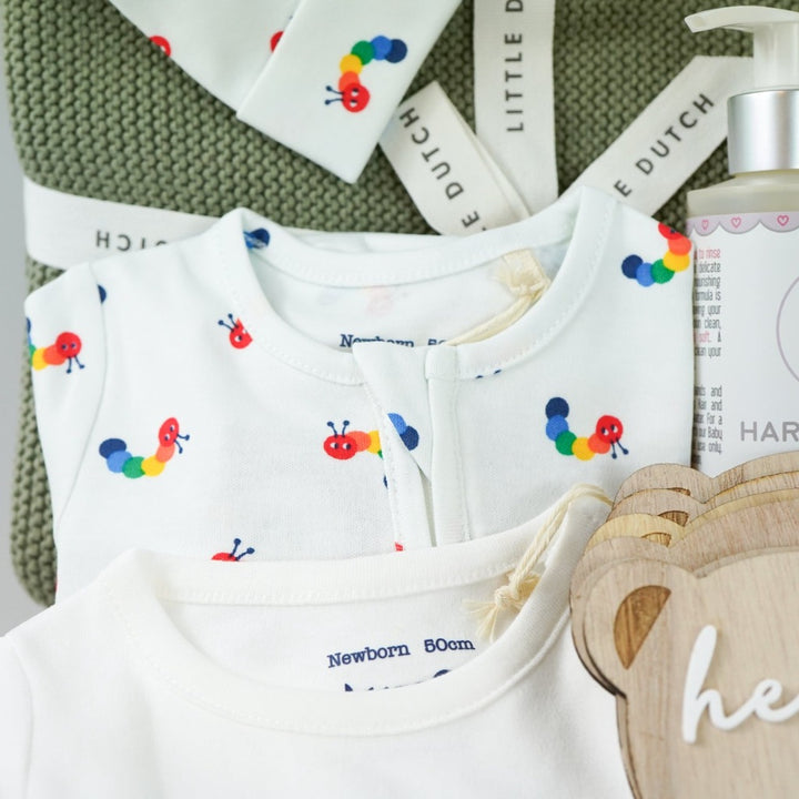 organic baby hamper, sage green organic baby blanket, white baby organic clothing nset with rainbow coloured catterpillars includes baby sleepsuit, baby hat with ears and bodysuit, organic baby wash, wooden baby milestone discs, yellow organic soft giraffe