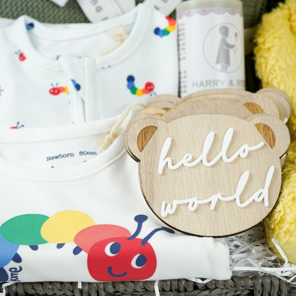 organic baby hamper, sage green organic baby blanket, white baby organic clothing nset with rainbow coloured catterpillars includes baby sleepsuit, baby hat with ears and bodysuit, organic baby wash, wooden baby milestone discs, yellow organic soft giraffe