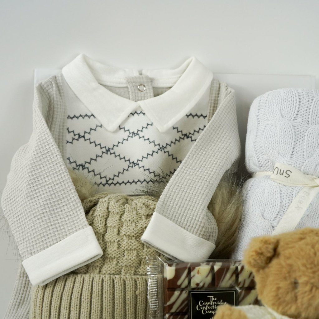 neutral baby hamper, spanish baby romper, white cotton baby wrap, baby booties, soft brown teddy with a jumper, chocolate slab