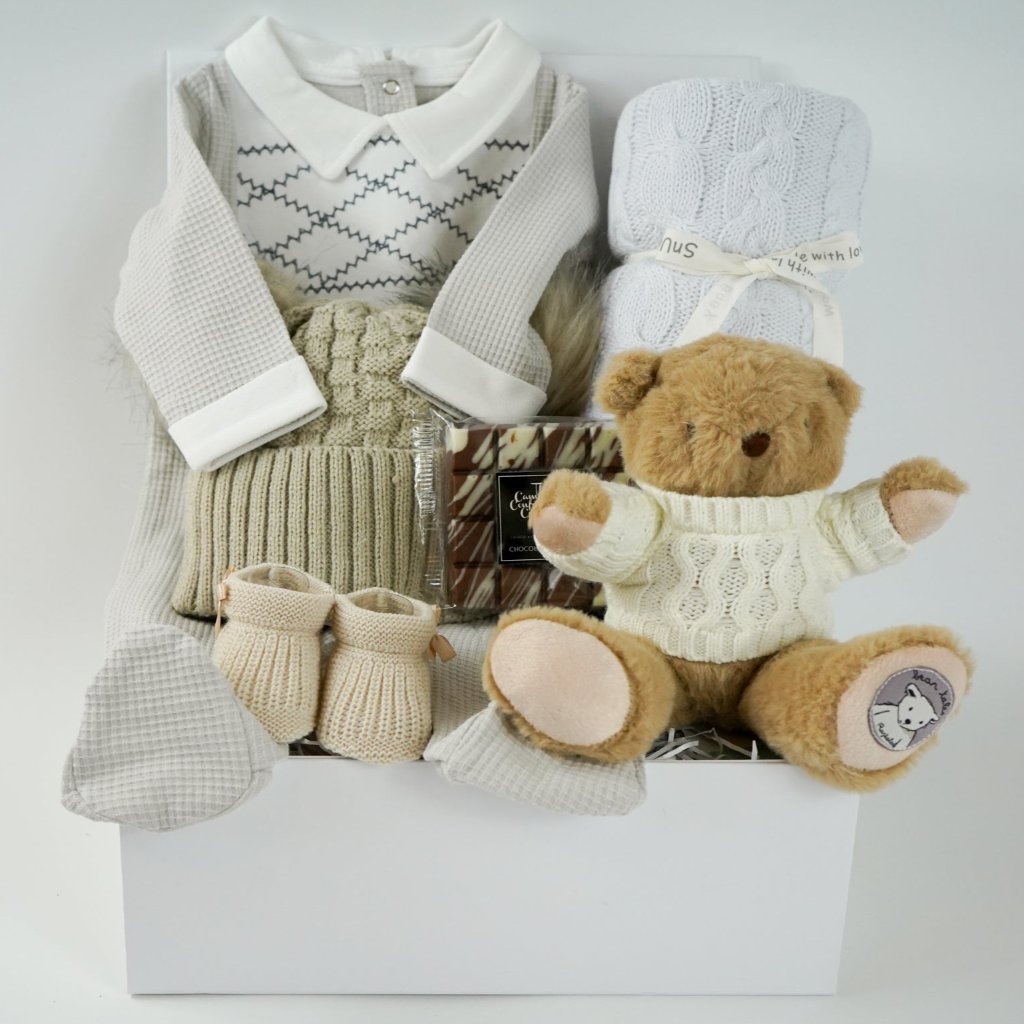 neutral baby hamper, spanish baby romper, white cotton baby wrap, baby booties, soft brown teddy with a jumper, chocolate slab