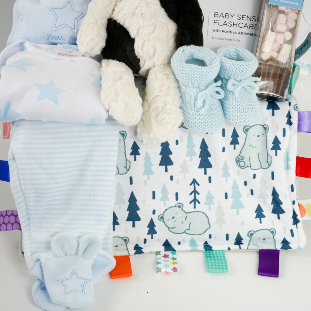 baby boy hamper with velour baby clothing set in blue, soft baby comforter with taggies, blue knit booties, cow soft toy, sensory cards , chocolate spoon