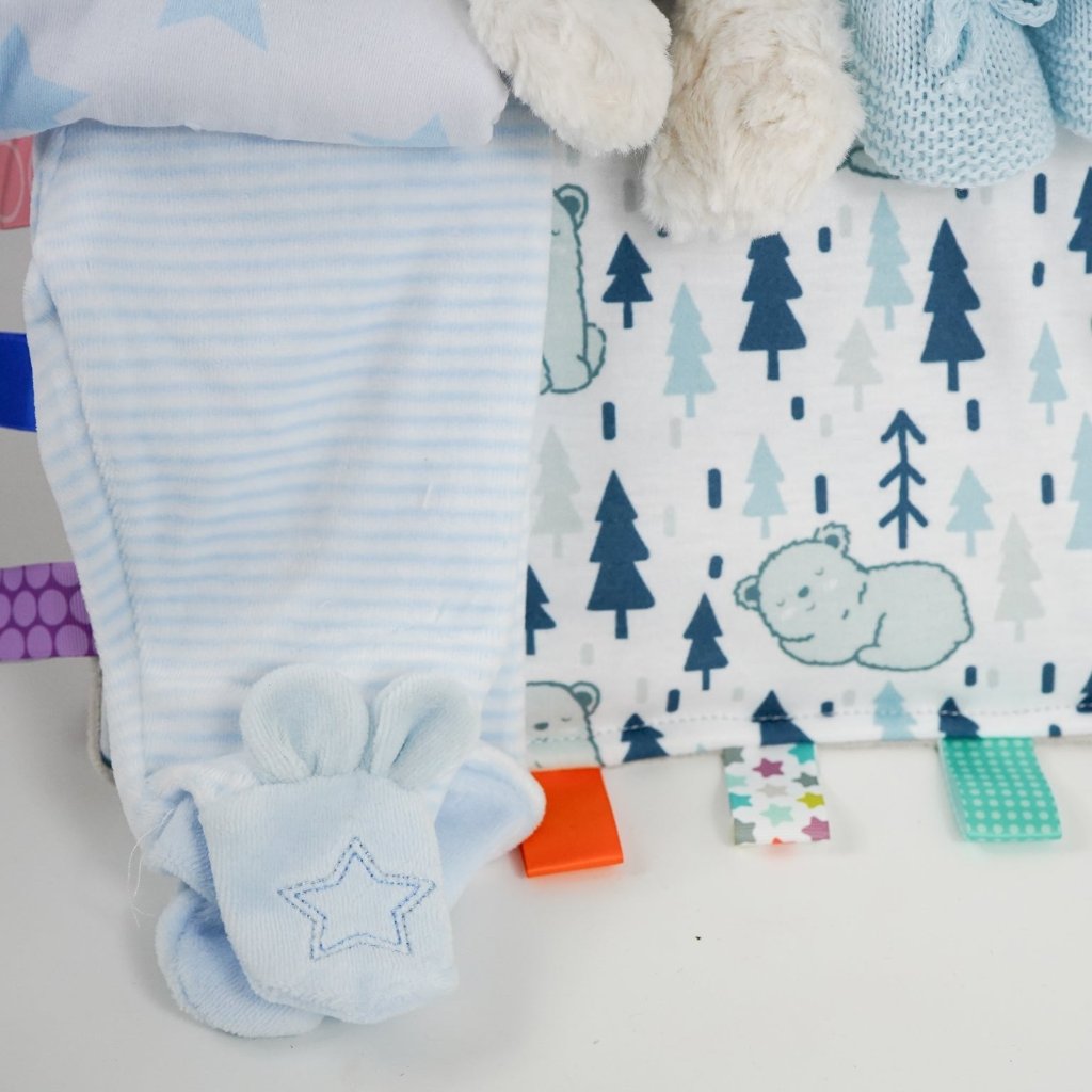 baby boy hamper with velour baby clothing set in blue, soft baby comforter with taggies, blue knit booties, cow soft toy, sensory cards , chocolate spoon