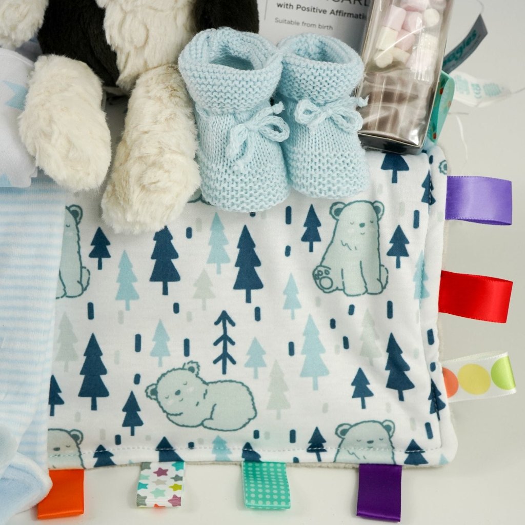 baby boy hamper with velour baby clothing set in blue, soft baby comforter with taggies, blue knit booties, cow soft toy, sensory cards , chocolate spoon