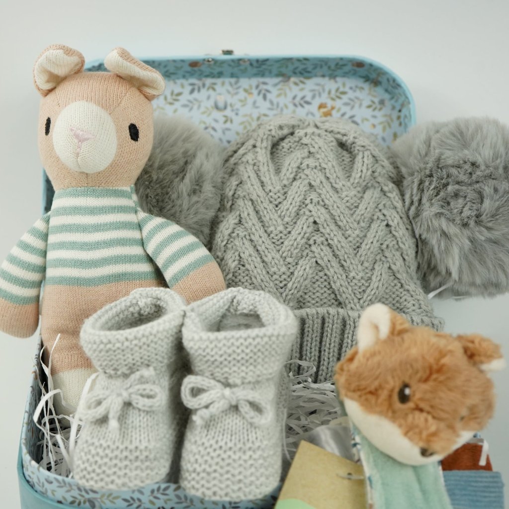 small case with soft knit baby rabbit toy, cuddly fox head wrist rattle, knit booties and double pompom grey knit baby hat