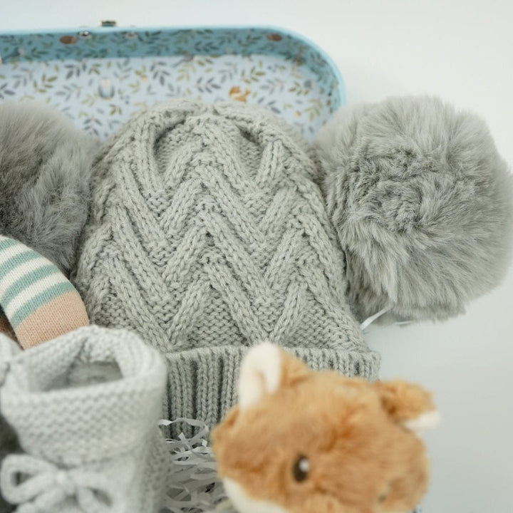 small case with soft knit baby rabbit toy, cuddly fox head wrist rattle, knit booties and double pompom grey knit baby hat