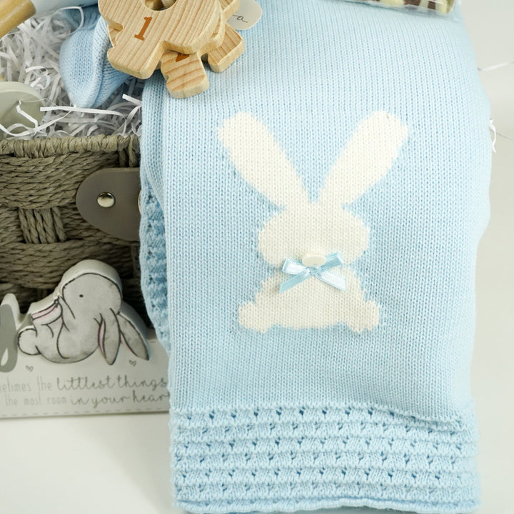 luxury baby and new parents hamper gift, blue baby blanket with white rabbit, knit blue romper with feet and white bunny, maracas, wooden teething key ring, small bottle of freixenet, chocolate, Little Dutch baby bunny milestone cards in a box, soft blue bunny in a velour pj's