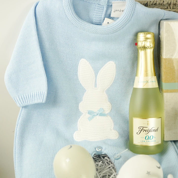 luxury baby and new parents hamper gift, blue baby blanket with white rabbit, knit blue romper with feet and white bunny, maracas, wooden teething key ring, small bottle of freixenet, chocolate, Little Dutch baby bunny milestone cards in a box, soft blue bunny in a velour pj's