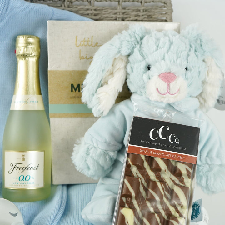 luxury baby and new parents hamper gift, blue baby blanket with white rabbit, knit blue romper with feet and white bunny, maracas, wooden teething key ring, small bottle of freixenet, chocolate, Little Dutch baby bunny milestone cards in a box, soft blue bunny in a velour pj's