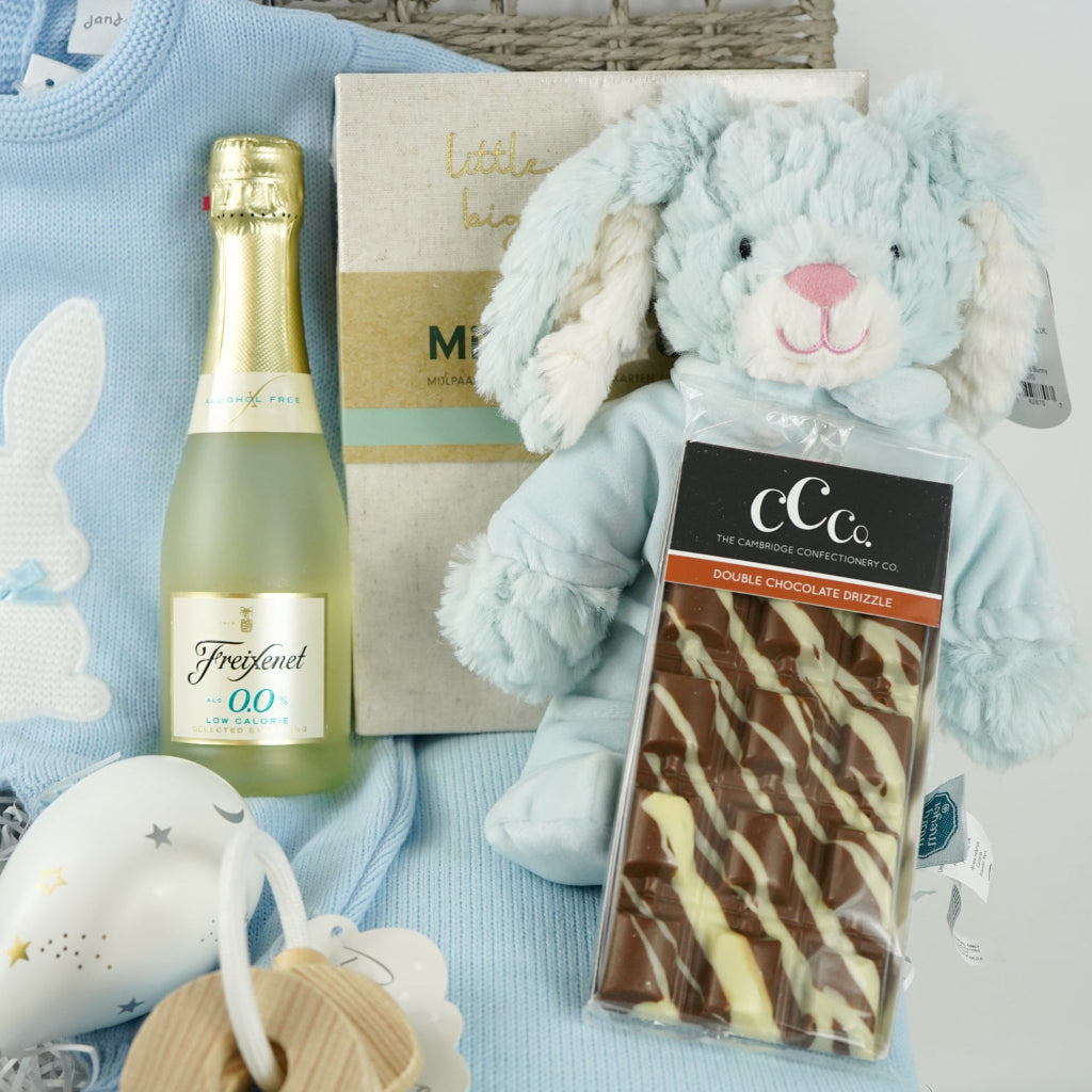 luxury baby and new parents hamper gift, blue baby blanket with white rabbit, knit blue romper with feet and white bunny, maracas, wooden teething key ring, small bottle of freixenet, chocolate, Little Dutch baby bunny milestone cards in a box, soft blue bunny in a velour pj's