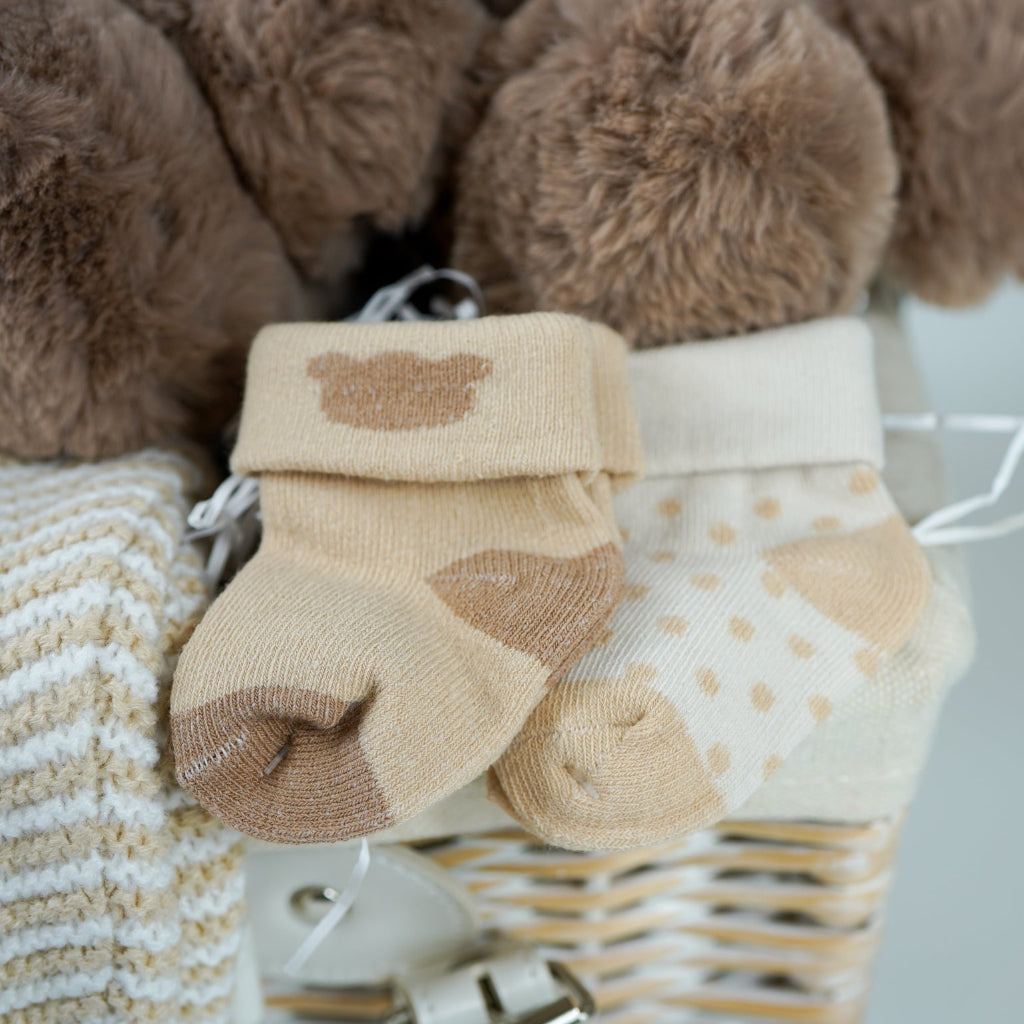 teddy bear themed baby hamper, beige and white baby knit clothing set with jumper, stripe knit leggings, hat and mittens, fabric baby book, 2 pairs of cream baby socks with teddy bear design , fabric baby book, baby shampoo and body wash, fabric book