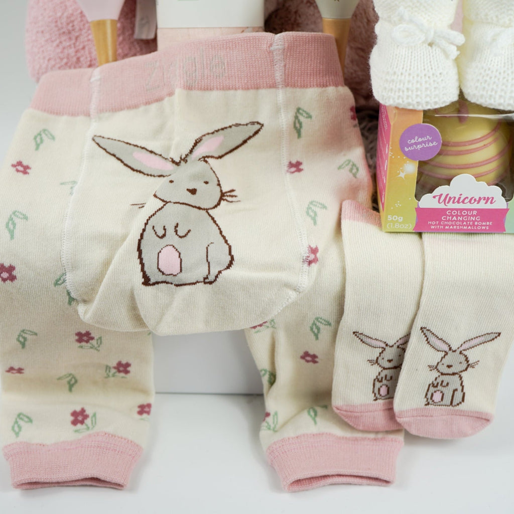 pink bunny baby hamper, pink hooded towel with bunny ears, soft bunny rabbit, bunny muslin, pink knit baby girl leggings with bunny on the  bum and matching socks with bunny, maracas in pin and grey with bunny face, white booties, , white chocolate bomb