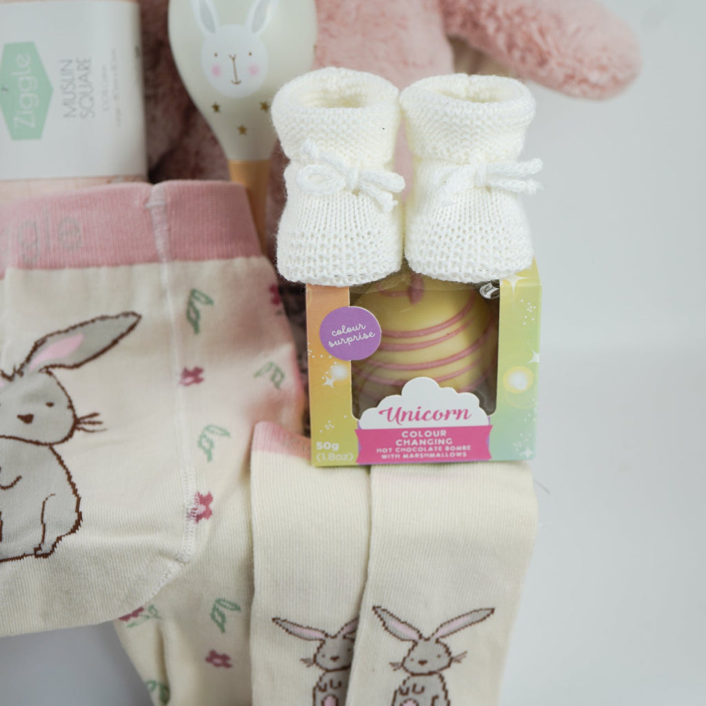 pink bunny baby hamper, pink hooded towel with bunny ears, soft bunny rabbit, bunny muslin, pink knit baby girl leggings with bunny on the  bum and matching socks with bunny, maracas in pin and grey with bunny face, white booties, , white chocolate bomb