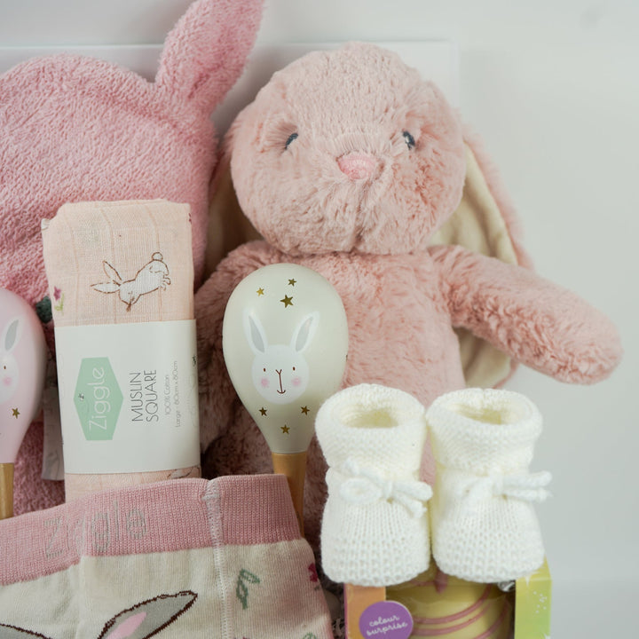 pink bunny baby hamper, pink hooded towel with bunny ears, soft bunny rabbit, bunny muslin, pink knit baby girl leggings with bunny on the  bum and matching socks with bunny, maracas in pin and grey with bunny face, white booties, , white chocolate bomb