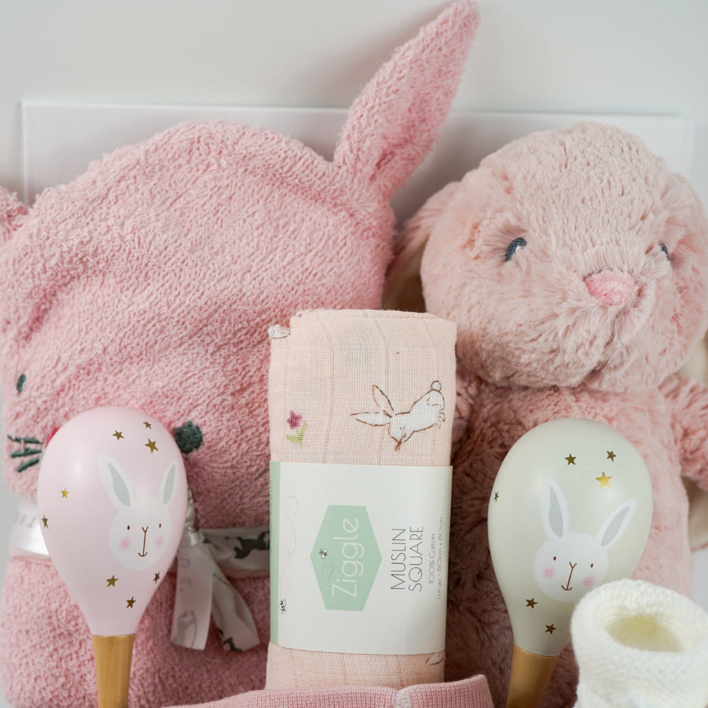 pink bunny baby hamper, pink hooded towel with bunny ears, soft bunny rabbit, bunny muslin, pink knit baby girl leggings with bunny on the  bum and matching socks with bunny, maracas in pin and grey with bunny face, white booties, , white chocolate bomb