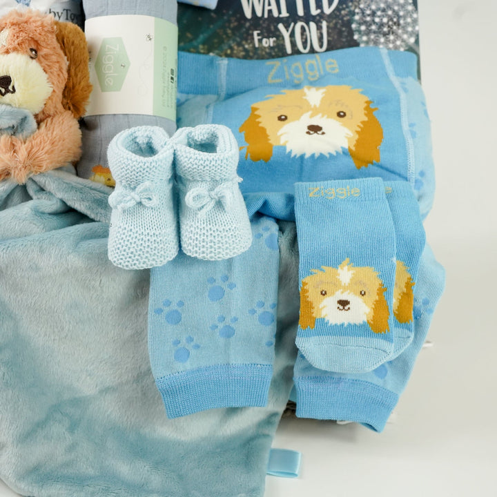 baby boy hamper box with blue puppy baby comforter with taggies, blue legging with a puppy on the bum, blue socks with puppy head, baby blue booties,  blue baby muslin with puppy, blue knot hat with puppy, blue cellular baby blanket, 'The world waited for you ' book