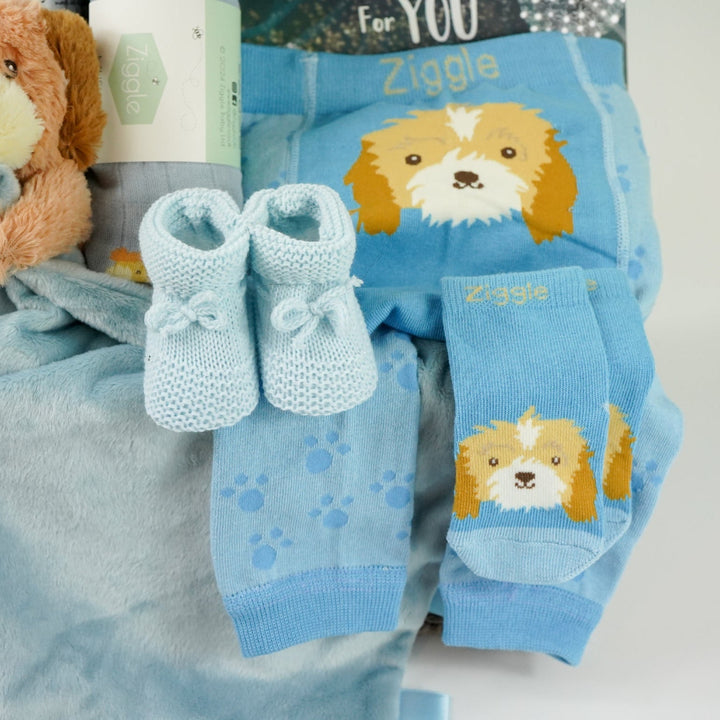 baby boy hamper box with blue puppy baby comforter with taggies, blue legging with a puppy on the bum, blue socks with puppy head, baby blue booties,  blue baby muslin with puppy, blue knot hat with puppy, blue cellular baby blanket, 'The world waited for you ' book