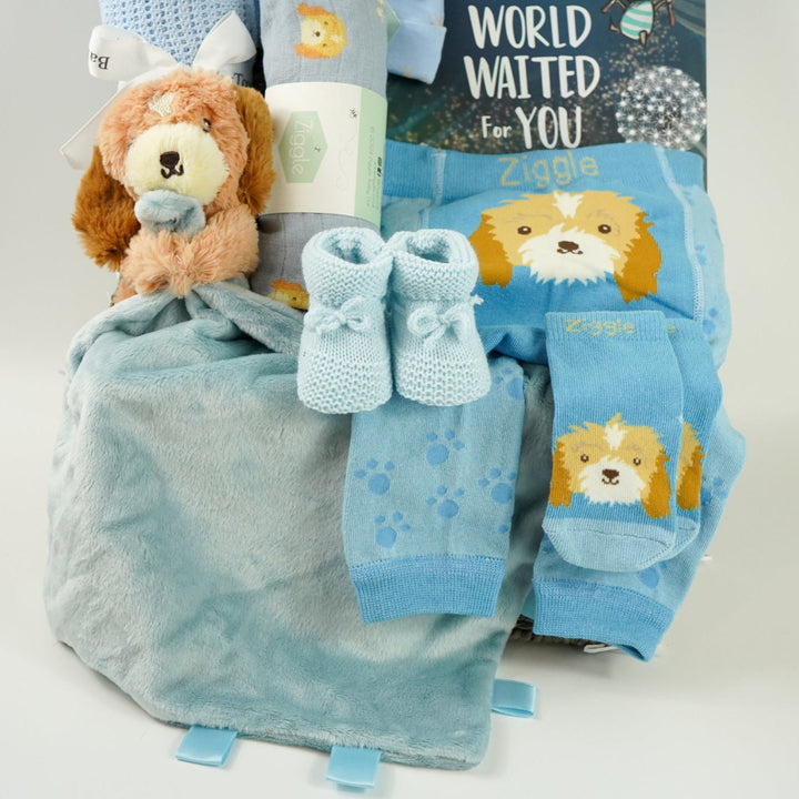 baby boy hamper box with blue puppy baby comforter with taggies, blue legging with a puppy on the bum, blue socks with puppy head, baby blue booties,  blue baby muslin with puppy, blue knot hat with puppy, blue cellular baby blanket, 'The world waited for you ' book