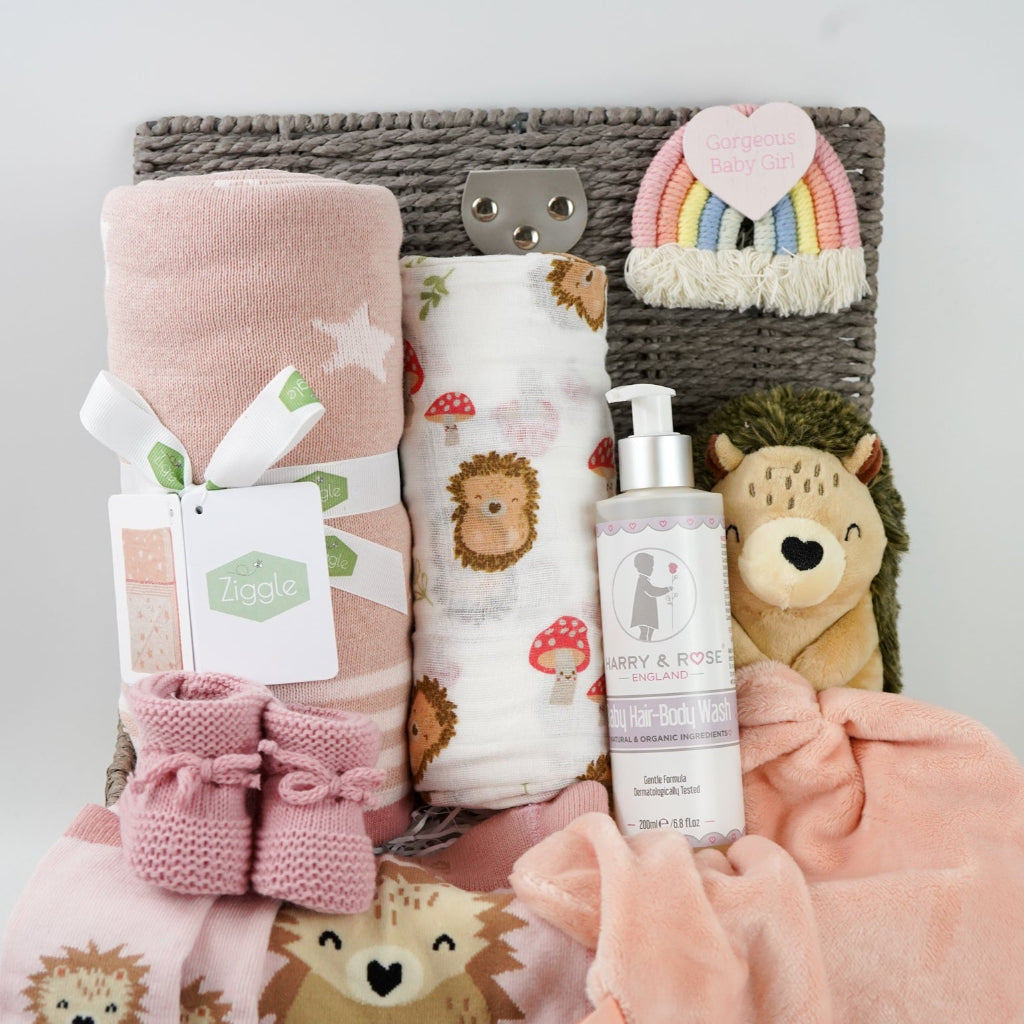 hedgehog themed baby hamper with pink striped hedgehog knit baby leggings and matching socks, baby pink star blanket, baby swaddle with hedgehogs , hedgehoge taggie comforter, baby knit booties, organic baby bath
