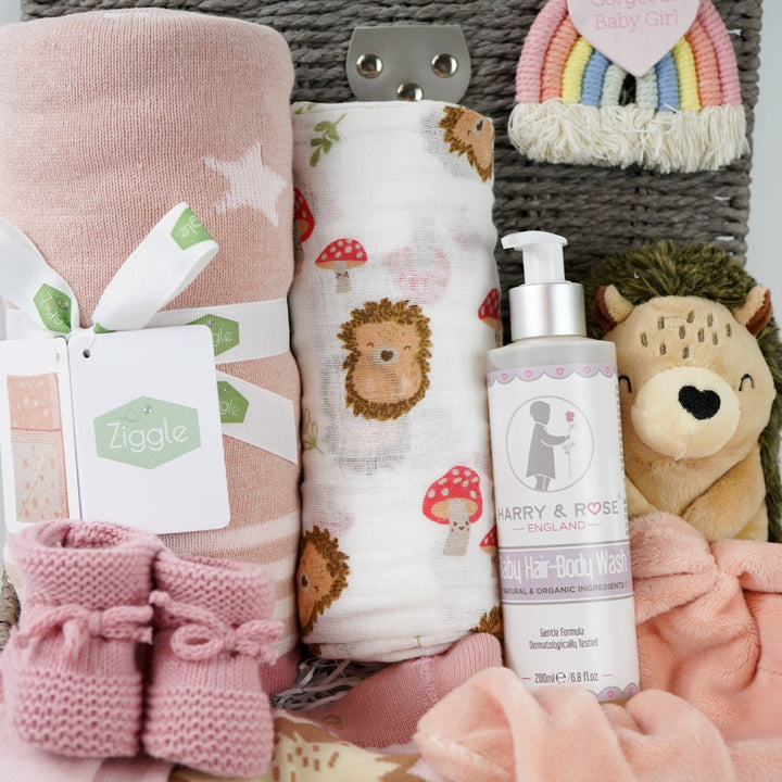 hedgehog themed baby hamper with pink striped hedgehog knit baby leggings and matching socks, baby pink star blanket, baby swaddle with hedgehogs , hedgehoge taggie comforter, baby knit booties, organic baby bath