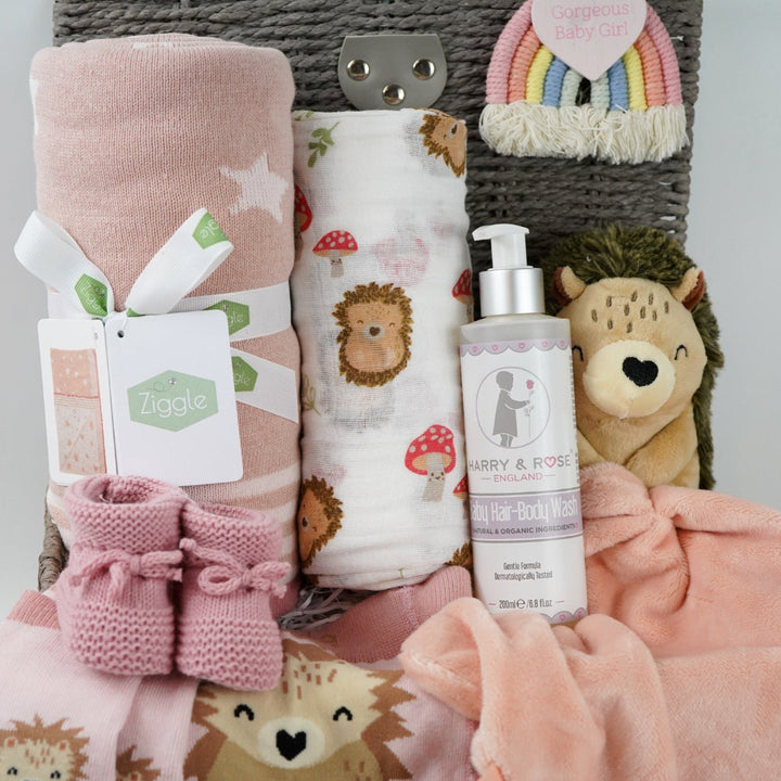 hedgehog themed baby hamper with pink striped hedgehog knit baby leggings and matching socks, baby pink star blanket, baby swaddle with hedgehogs , hedgehoge taggie comforter, baby knit booties, organic baby bath