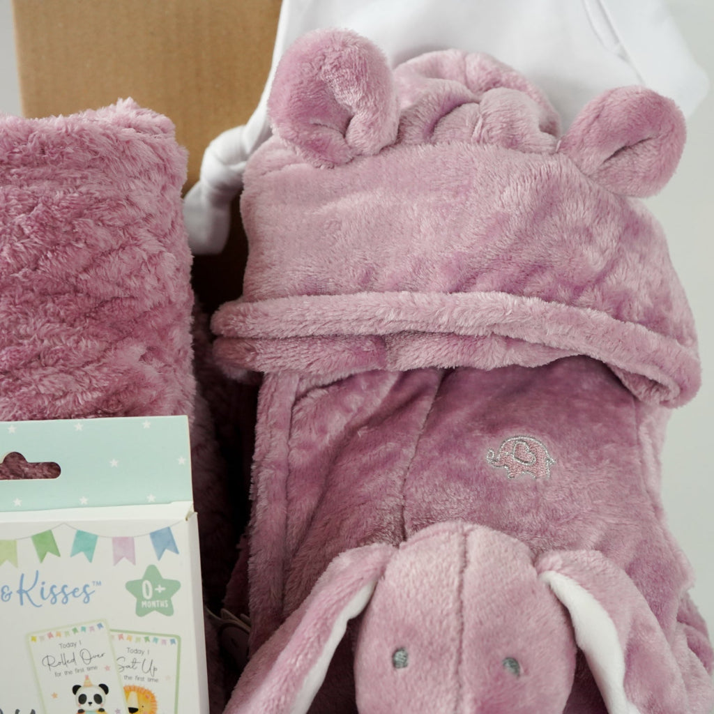 aby gift set with pink plush baby comforter in pink with matching dressing gown and blanket all in a dusky pink fleece , baby white knot hat and white knit booties and baby milestone cards packaged in a  box