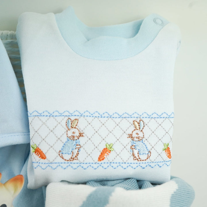 uxury baby boy gift hamper Peter rabbit themed baby clothing set includes a pale blue jacket with peter rabbit embroidered, peter rabbit comforter and soft toy, peter rabbit slippers, luxury candle, baby toiletries, cellular blanket, peter rabbit blue and white blankets with fluffy tail, Sophie La Girafee