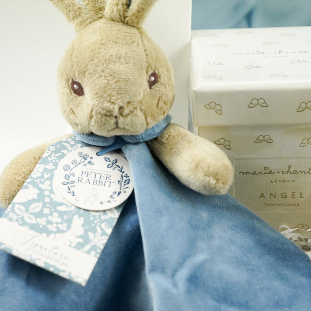 uxury baby boy gift hamper Peter rabbit themed baby clothing set includes a pale blue jacket with peter rabbit embroidered, peter rabbit comforter and soft toy, peter rabbit slippers, luxury candle, baby toiletries, cellular blanket, peter rabbit blue and white blankets with fluffy tail, Sophie La Girafee