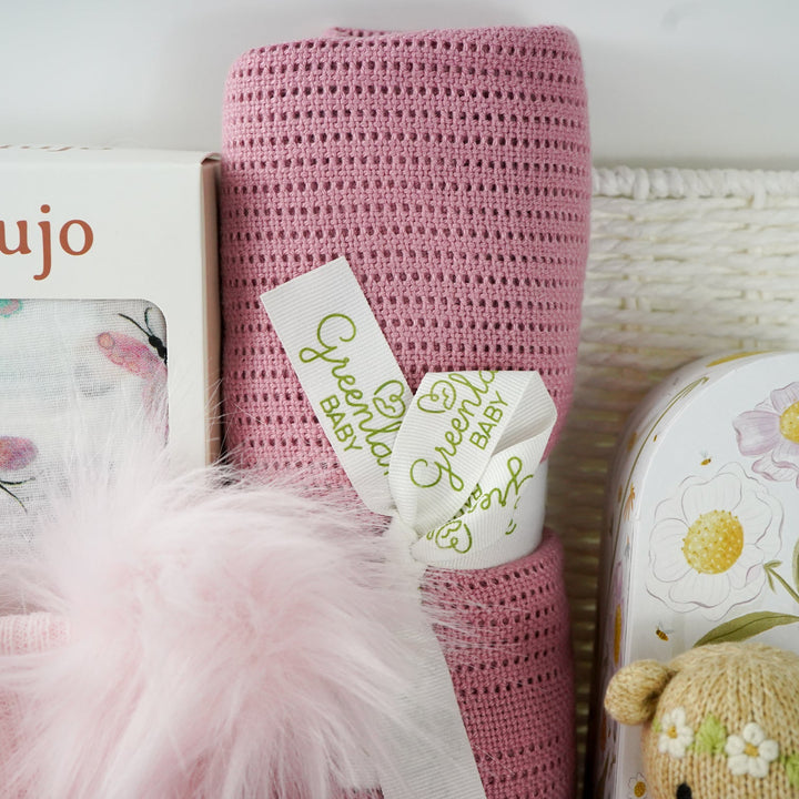 baby and mum to be hamper with luxury pink baby grow, white swaddle with butterflies, pink fluffy double pom pom hat, luxury bump candle, deep pink bamboo cellular blanket, Cuddle & Kin Artisan knitted teddy with own house, pink baby booties with a bow