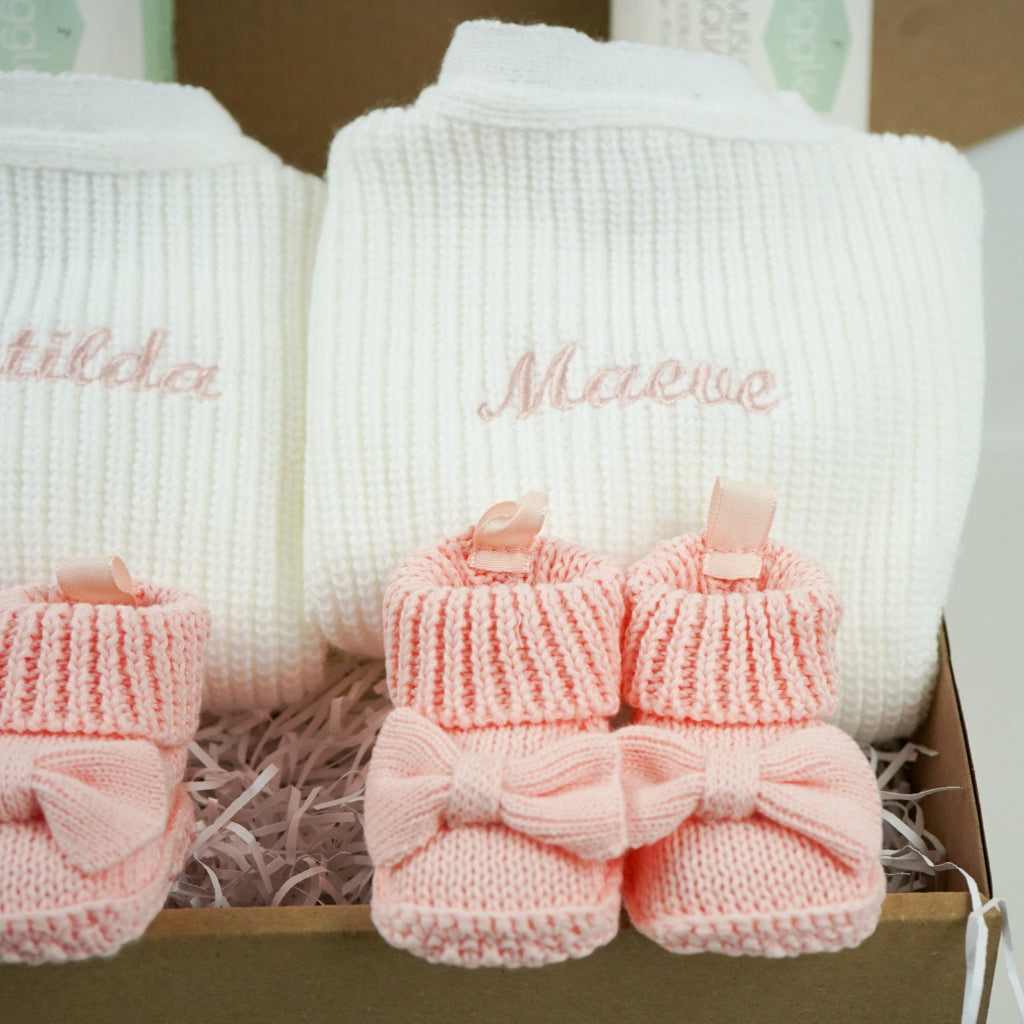 baby gifts in a eco friendly outer box includes white knit baby ribbed cardigans x 2 and pink booties with bows x 2 and pink muslin squares with bunnies x 2 