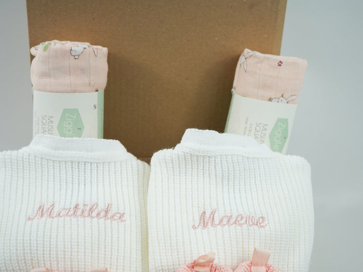 baby gifts in a eco friendly outer box includes white knit baby ribbed cardigans x 2 and pink booties with bows x 2 and pink muslin squares with bunnies x 2 